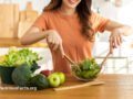 A woman happily preparing a fresh salad