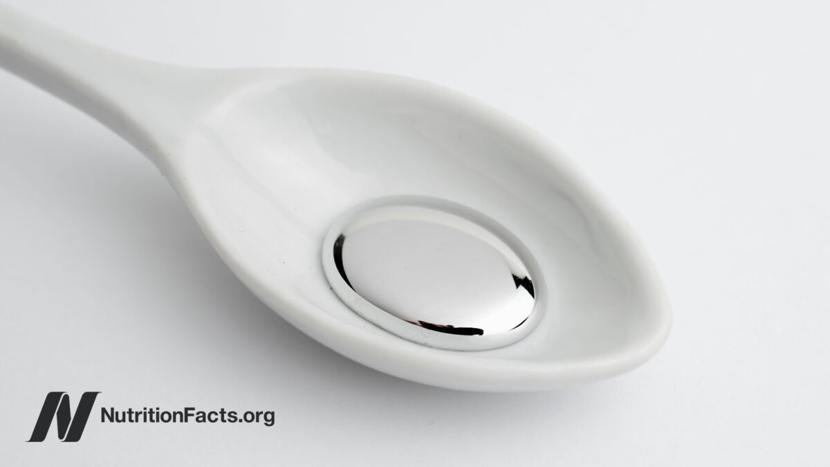 White spoon holding liquid mercury on a white background