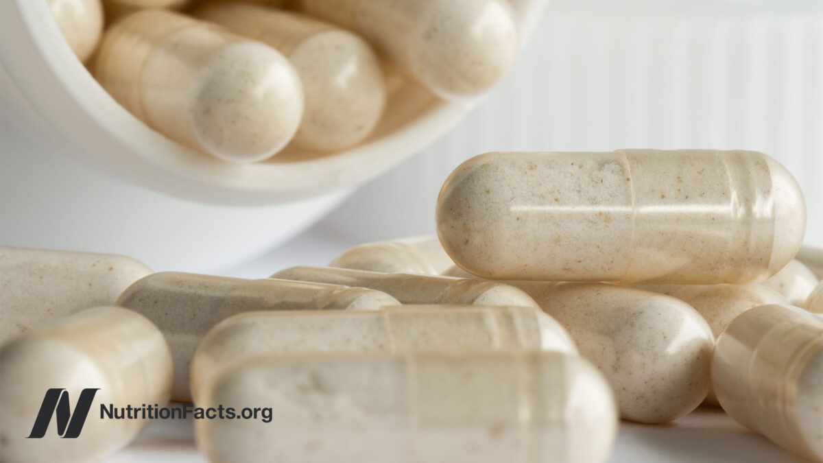 White pill bottle with supplement capsules pouring out