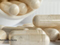 White pill bottle with supplement capsules pouring out