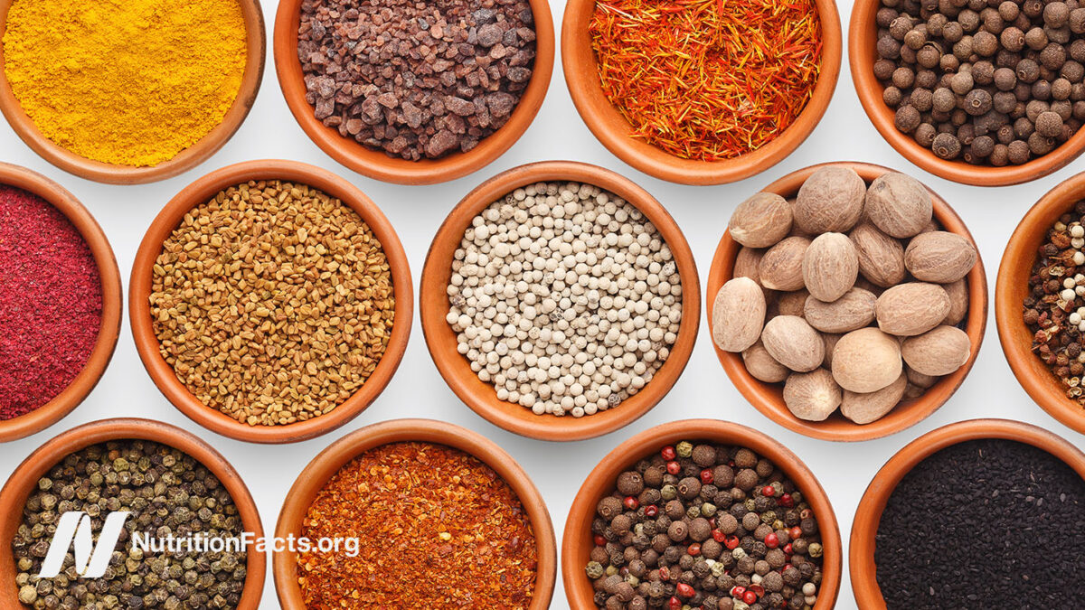 An overhead view of a variety of spices and herbs in bowls