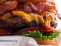 Closeup side view of a cheese burger with bacon