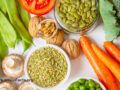 An array of whole plant foods, including green beans, avocado, cilantro, tomato, pepper