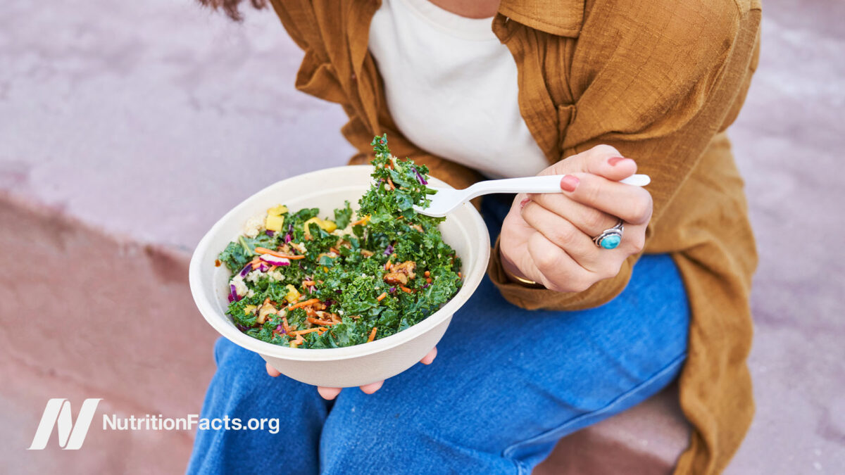 Person sitting down and eating a mixed kale salad