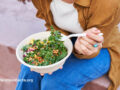 Person sitting down and eating a mixed kale salad