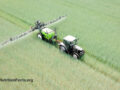 Overhead view of a tractor spraying glyphosate over a green field