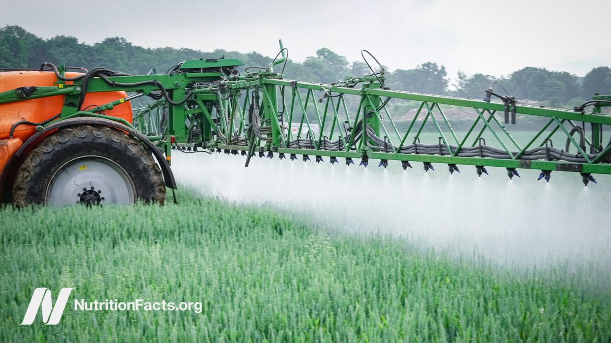 Side view of a tractor spraying a field with glyphosate