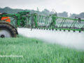 Side view of a tractor spraying a field with glyphosate