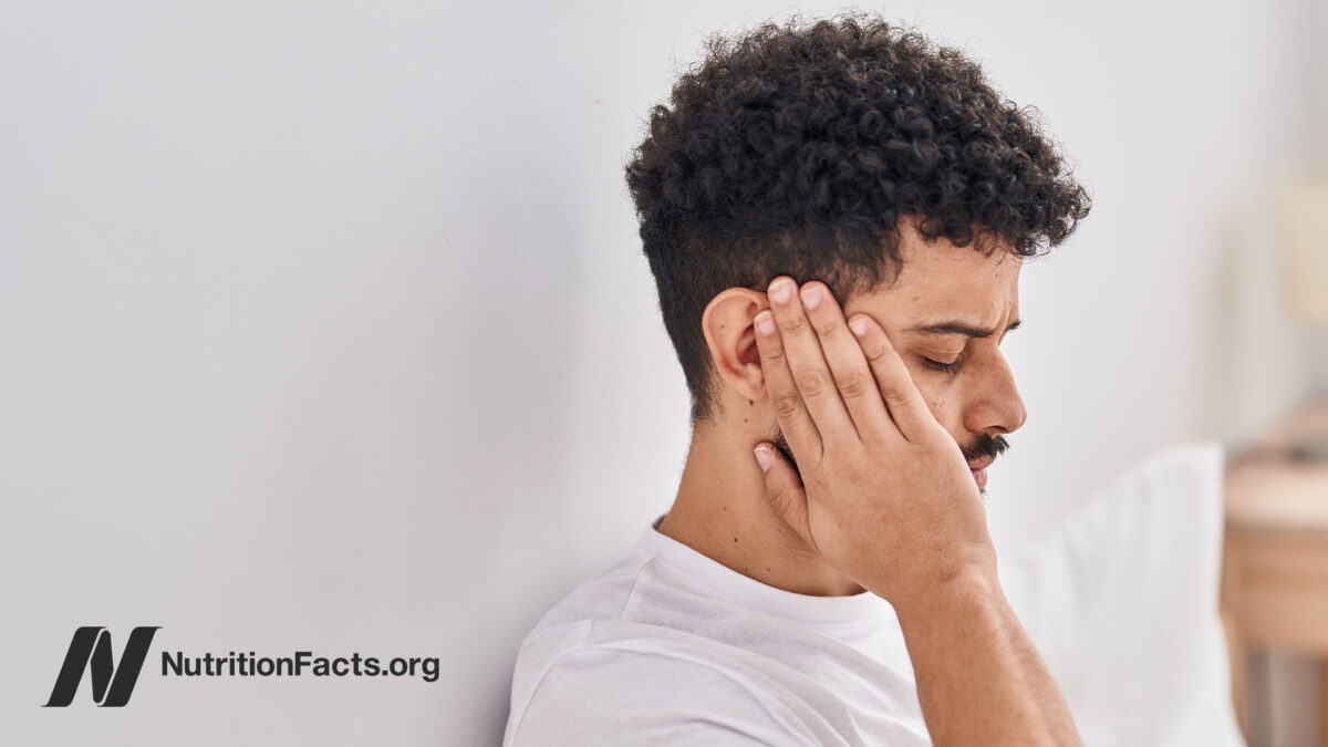 Side view of a person holding their ear