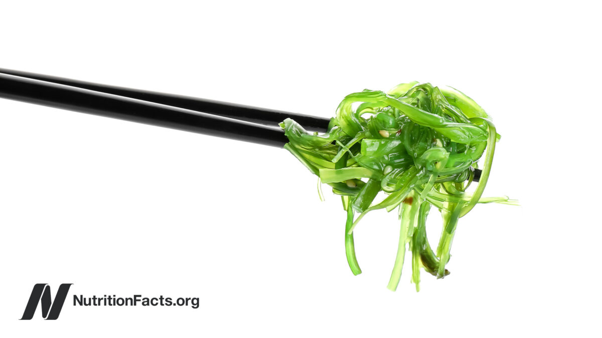 Black chopsticks holding seaweed salad