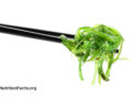 Black chopsticks holding seaweed salad