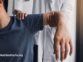 Physical therapist holding up a person’s arm and resting a hand on their shoulder