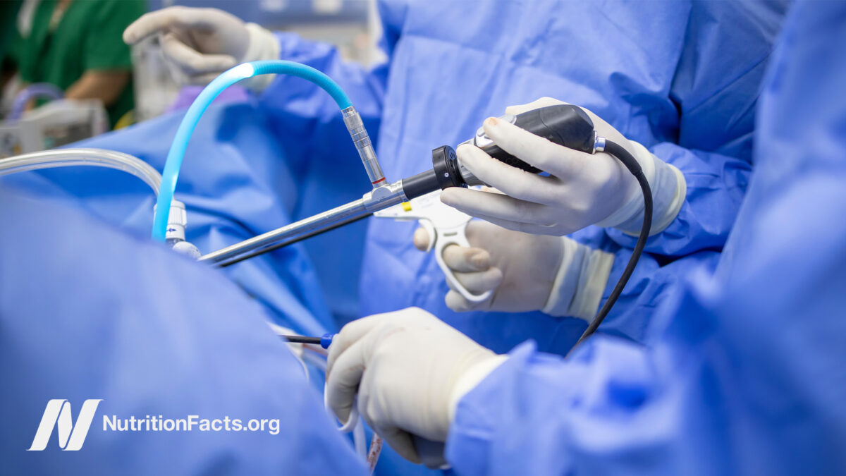 Surgeons in blue scrubs wearing gloves and holding surgical instruments during a procedure
