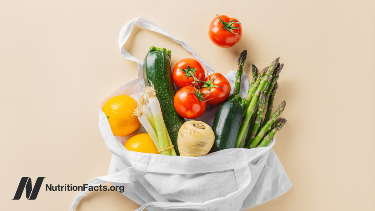 Canvas tote bag full of produce falling out, such as zucchini, tomato, asparagus