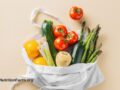 Canvas tote bag full of produce falling out, such as zucchini, tomato, asparagus