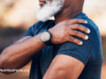 Older person of color holding their shoulder in discomfort
