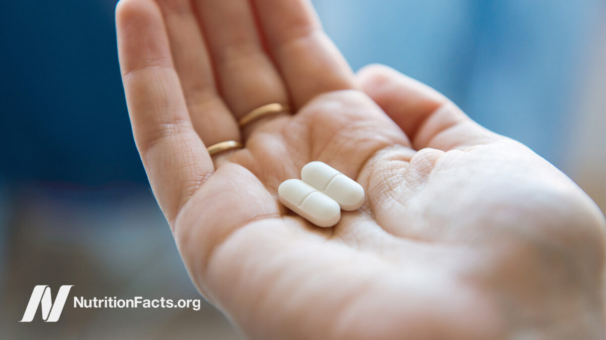 Closeup view of a hand holding two ibuprofen pills