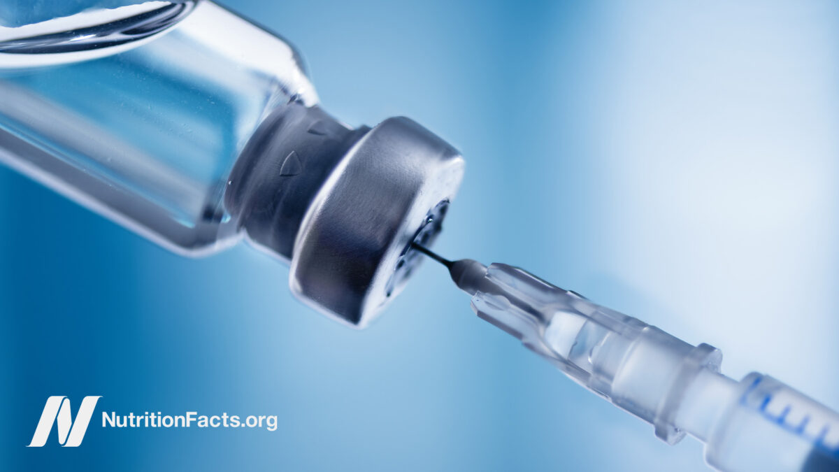 Closeup view of a medical needle inserting into a small bottle of steroid