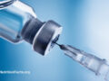 Closeup view of a medical needle inserting into a small bottle of steroid
